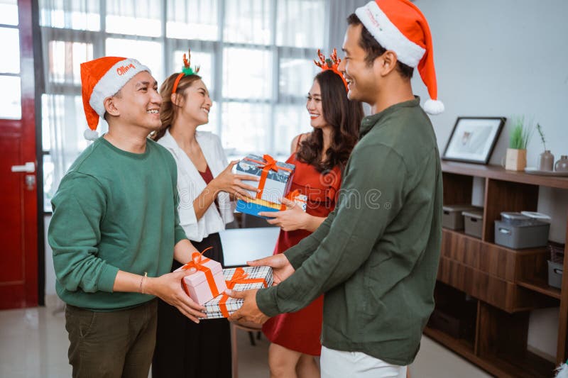 Joyful Christmas Gift Exchange Among Friends In Santa Hats Celebrating